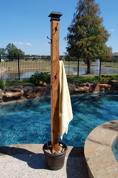 an umbrella stand next to a pool with a towel hanging from it's pole