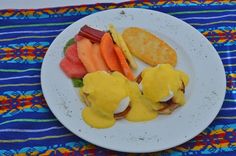 a white plate topped with eggs benedict and fruit