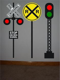 three traffic lights and two railroad crossing signs on a wall in a room with carpeted flooring