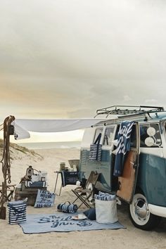 an old vw camper van parked on the beach with its surfboard propped up against it