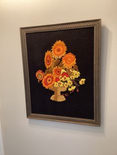 a painting hanging on the side of a wall with sunflowers and other flowers in it