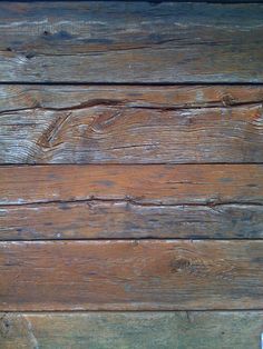 an old wooden wall with peeling paint and wood grains on the bottom part of it