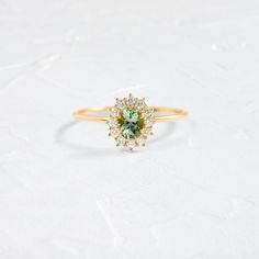 a ring with an oval shaped green stone surrounded by small white and yellow diamond accents