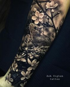 a black and white tattoo with an animal on it's arm, surrounded by flowers