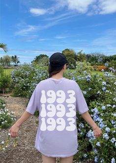 a woman standing in front of blue flowers wearing a t - shirt with the words feel free on it