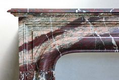 an old fireplace with red and green paint on it's mantle, next to a white wall