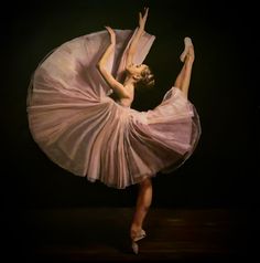 a young ballerina in a pink tutu and ballet shoes is doing an acrobatic move