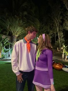 a man standing next to a woman in a purple dress