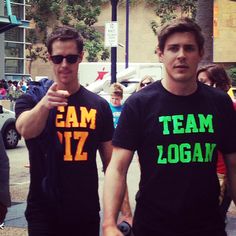 two men wearing team zoga t - shirts walking down the street