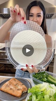 a woman holding up a plate with food on it in front of her face and vegetables