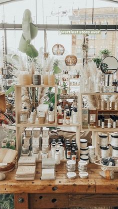 a wooden table topped with lots of jars and containers filled with plants in front of a window