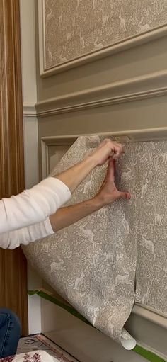 a woman is working on the wall with fabric