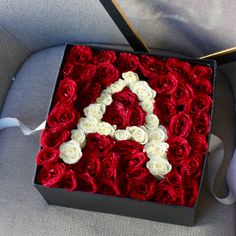 a red box with white roses and the letter a in it is sitting on a chair