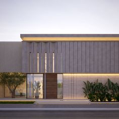 an exterior view of a modern building with plants and trees in the foreground, at dusk