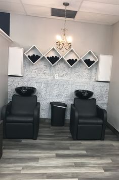 two black chairs sitting next to each other in front of a wall with shelves on it