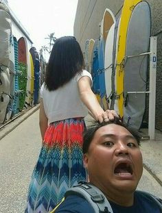 a man standing next to a woman with surfboards on the back of his head