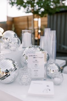 the table is set up with disco balls and place cards for guests to sign in