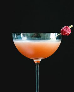 a pink cocktail garnished with a raspberry