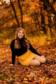 a beautiful young woman sitting on the ground surrounded by leaves in an autumn forest photo