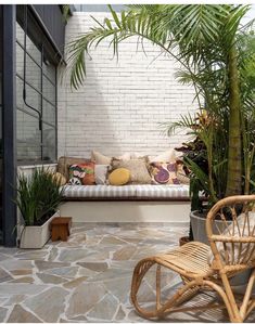 an outdoor seating area with potted plants on the side and a wicker chair next to it