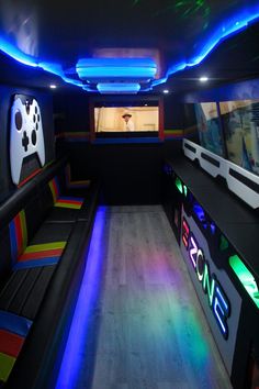 the interior of a party bus with neon lights and video game controllers on the seats