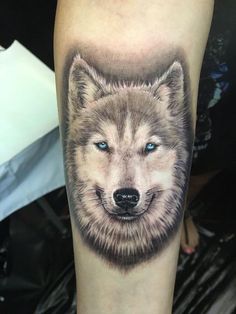 a wolf tattoo on the arm with blue eyes and an animal's head is shown