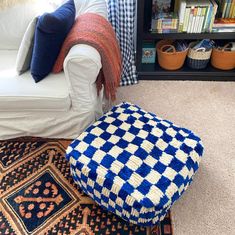 a blue and white ottoman sitting on top of a rug next to a book shelf