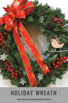 a christmas wreath with red and gold ribbon on the front, featuring a sleigh ornament