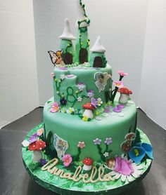 a green cake decorated with fairy land and flowers