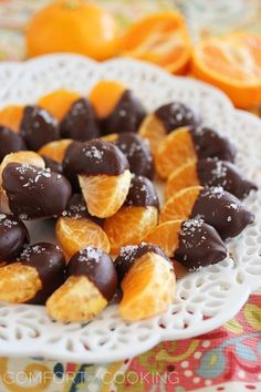 oranges and chocolate covered candies on a white plate