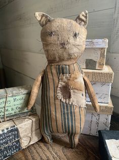 a stuffed cat sitting on top of a wooden table next to stacks of old books