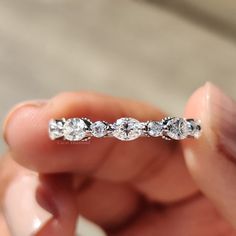 a hand holding a diamond ring in it's left hand, with three diamonds on the band