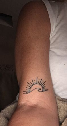 a person with a tattoo on their arm and the sun in the sky behind them