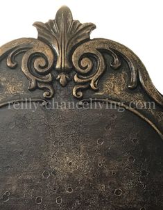 an ornate metal headboard with gold leaf and scrolls on the top, against a white background