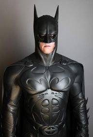 a man dressed as batman standing in front of a wall