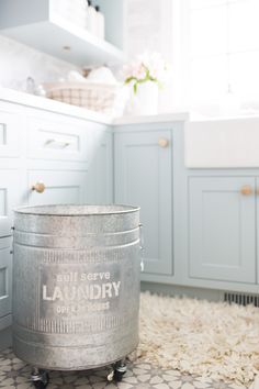 a laundry bucket sitting on top of a rug in a kitchen next to a sink