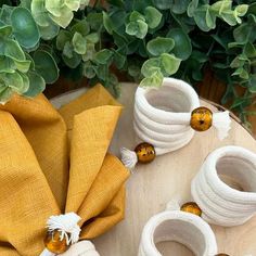 the table is set with yellow napkins and white vases on top of it