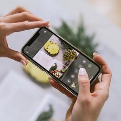 a woman holding up her cell phone to take a photo with pineapples on it