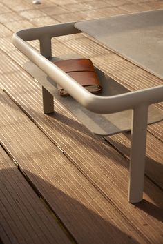 a table with a wallet on it sitting on top of a wooden floor next to a fence