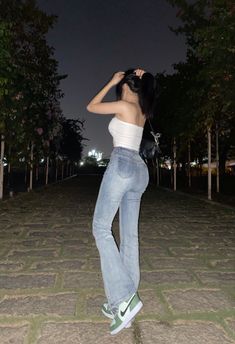 a woman standing on the ground with her hands behind her head and looking up at the sky