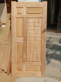 a wooden door sitting on top of a pile of wood planks next to a building