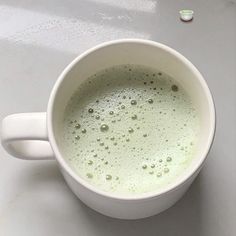 a white cup filled with liquid on top of a table