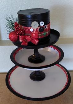 three tiered cake stand decorated with red and black ribbon, buttons and bows on top