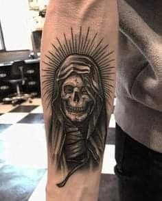 a person with a tattoo on their arm that has a skull in the middle and a headdress