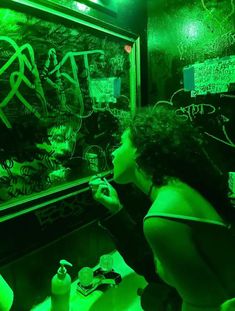 a woman is writing on a blackboard in a dark room with green lights and graffiti