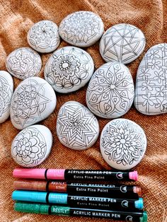 some rocks with designs on them next to crayon markers and marker pencils