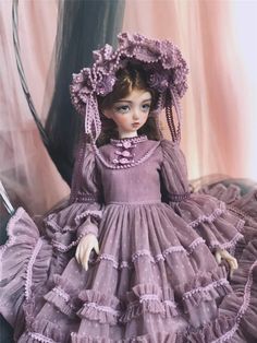 a doll is wearing a purple dress and bonnet