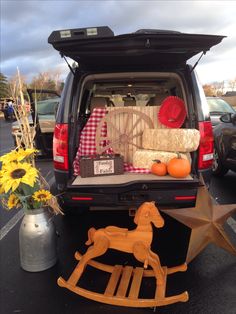 the back end of a van with an open trunk and wooden rocking horse on it