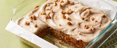 a glass casserole dish filled with cake and frosting on top of a green tablecloth