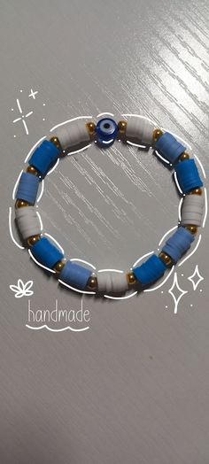 a blue and white beaded bracelet with gold accents on a silver surface, handmade